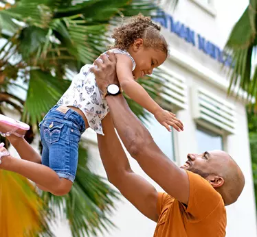 Father happily playing with his daughter, lifting her into the air with joy and laughter.